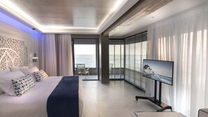 Ein modernes Hotelzimmer mit Bett, Fernseher und einem Balkon mit Meerblick.