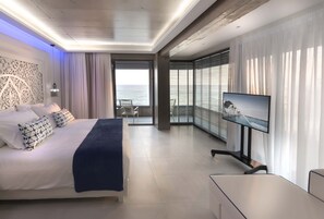 Une chambre d’hôtel moderne équipée d’un lit, d’une télévision et d’un balcon avec vue sur la mer.