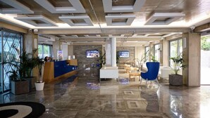 Eine großzügige Lobby mit einer Rezeption, einer Sitzecke und einer Steinwand.