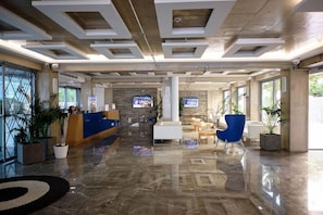 Un hall d’entrée spacieux comprenant un comptoir d’accueil, un espace salon et un mur en pierre.