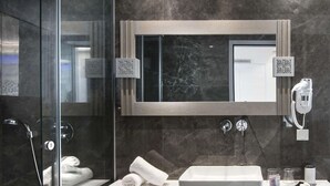 Ein modernes Badezimmer mit einer Duschkabine, einem weißen Waschbecken und einem großen Spiegel.