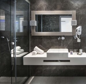 Une salle de bain moderne avec une douche à parois de verre, un lavabo blanc et un grand miroir.