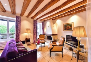 A furnished living room with a sofa, chairs, a fireplace, a television, and a window with curtains. - La Rouvenaz (Montreux)