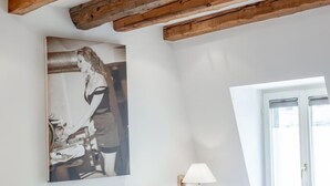 Une chambre à coucher avec un lit, des oreillers blancs, une lampe fixée au mur et une fenêtre.