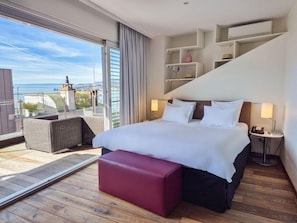 A modern hotel room with a large bed, a red bench, a balcony with a view, and built-in shelving. - La Rouvenaz (Montreux)