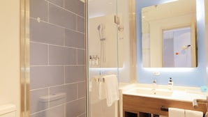 Ein modernes Badezimmer mit einer gläsernen Duschkabine, einem hölzernen Waschtisch und einem großen Spiegel.