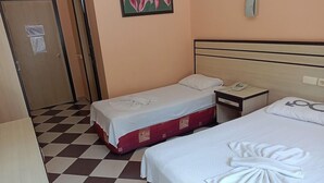 Una habitación de hotel con dos camas, piso a cuadros, una puerta y un cuadro en la pared.