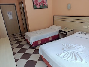 Una habitación de hotel con dos camas, piso a cuadros, una puerta y un cuadro en la pared.
