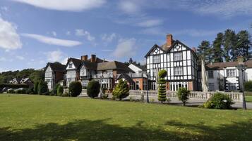 A traditional half-timbered house with a well-maintained lawn and a clear sky.