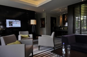 A modern hotel lobby with a flat-screen TV displaying a news program, a reception desk, and a seating area with a striped carpet. - The Golf Hotel Woodhall Spa (Woodhall Spa)
