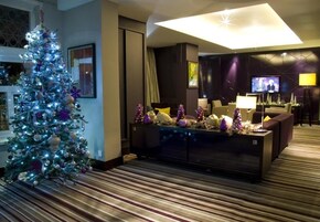 Un hall de hotel con un árbol de Navidad, un sofá, un televisor y una lámpara.