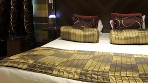 A hotel room with a large bed, two pillows, a nightstand, and a wall with a striped pattern.