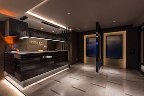 A modern hotel lobby with a reception desk, a fireplace, and a large screen. - Hotel C. Chiba Shiroi (Shiroi)