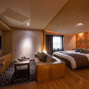 A hotel room with a bed, a sofa, a small table, and a TV.