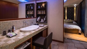 A hotel bathroom with a large mirror, a sink, and shelves with toiletries. - Hotel C. Chiba Shiroi (Shiroi)