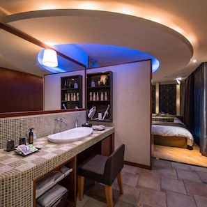 A hotel bathroom with a large mirror, a sink, and shelves with toiletries. - Hotel C. Chiba Shiroi (Shiroi)