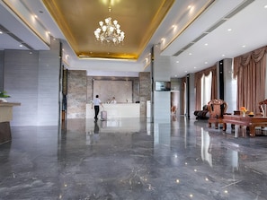 A hotel lobby with a marble floor, a reception desk, a chandelier, and a seating area with a sofa and armchairs. - The BLD International Hotel (Dongguan)