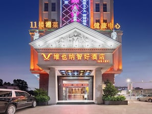 A hotel entrance with a prominent sign, a statue, and a neon sign above. - The BLD International Hotel (Dongguan)