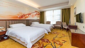 Habitación de hotel con dos camas, un televisor de pantalla plana, un escritorio y un gran mural en la pared.
