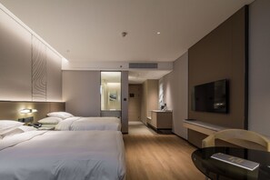 Ein Hotelzimmer mit zwei Betten, einem Fernseher, einem Schreibtisch und einem Sessel.