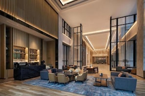 Eine großzügige Lobby mit Barbereich, Sitzgelegenheiten und einer hohen Decke mit Beleuchtung.