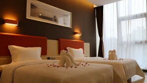 Habitación de hotel con dos camas, un ventanal grande y un cuadro en la pared.