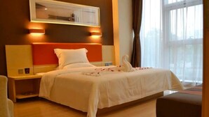 Habitación de hotel con cama, mesitas de noche, cortinas en una ventana y un aplique de pared.