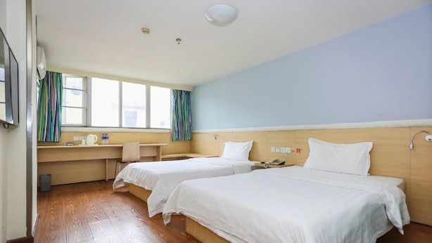 Ein Hotelzimmer mit zwei Betten, einem Schreibtisch und einem Fenster mit Vorhängen.