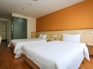 A hotel room with two beds, a wooden floor, and a plain orange wall. - 7 Days Inn Chengdu North Railway Train Station Square Branch (Chengdu)