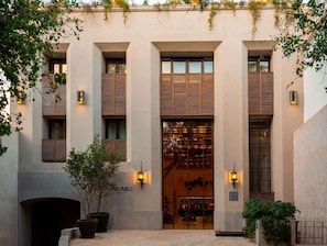 Fachada de edificio con amplias ventanas, entrada central con puerta de vidrio e iluminación empotrada.