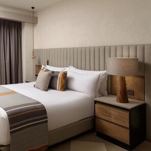 Una habitación de hotel con una cama, mesitas de noche, una lámpara y una cortina.