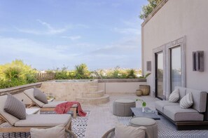 A rooftop terrace with lounge chairs, a sofa, a small table, and a staircase leading to a pool. - Numu Boutique Hotel (San Miguel de Allende)