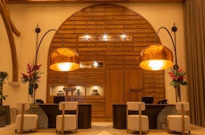 A reception area with a wooden wall, two pendant lights, a reception desk, and seating. - Numu Boutique Hotel (San Miguel de Allende)