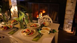 A dining table set for a meal with plates of food, glasses, and a fireplace in the background. - Feel & Live Hotel - Villas - Restaurant (Sapanca)