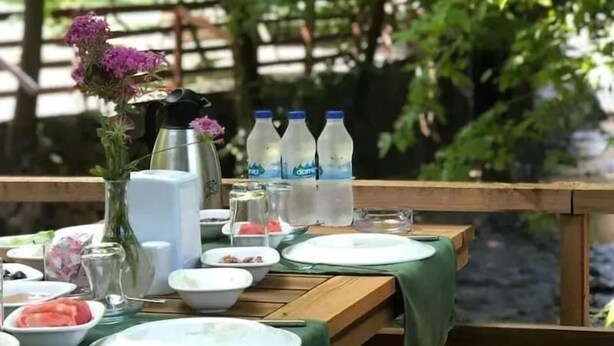 An outdoor dining table set with plates, bowls, and bottles, surrounded by chairs. - Feel & Live Hotel - Villas - Restaurant (Sapanca)