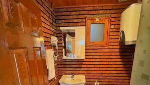 A compact bathroom with a wooden wall, a sink, a toilet, and a shower area. - Feel & Live Hotel - Villas - Restaurant (Sapanca)