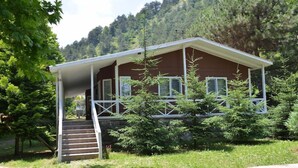 A two-story cabin with a porch, surrounded by trees and a mountainous backdrop. - Feel & Live Hotel - Villas - Restaurant (Sapanca)
