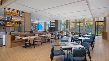 A modern restaurant with a long dining area, booths, and a bar area with shelves.