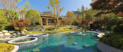 A swimming pool with a circular design, surrounded by landscaped gardens and a traditional building.