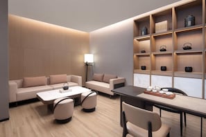 A modern hotel room with a sofa set, a dining table, and a tea display.