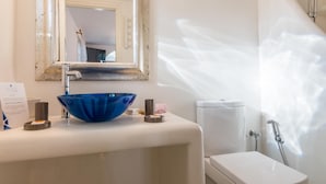 Ein Badezimmer mit Waschbecken in Weiß, einem blauen Becken, einer Toilette in Weiß und einer Dusche.