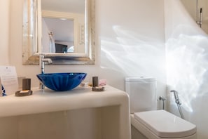 Une salle de bain avec un lavabo blanc, un bac bleu, des toilettes blanches et une douche.
