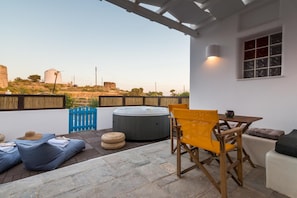 Um pátio externo com hidromassagem, área de estar e vista para moinhos de vento ao longe.