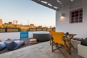 Um pátio externo com hidromassagem, área de estar e vista para moinhos de vento ao longe.