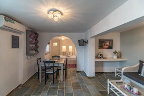 A modern interior with a dining area, a living space, and a hallway leading to a bedroom. - Eiriana Luxury Suites (Milos)