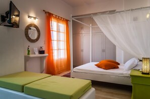 A bedroom with a bed, a nightstand, a mirror, and a wardrobe. - Eiriana Luxury Suites (Milos)