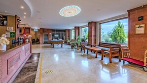 A hotel lobby with a reception desk, pool table, seating area, and large windows. - Troya Otel (Ezine)