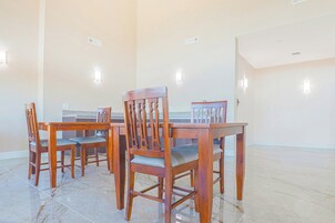 Un comedor con una mesa y sillas de madera, piso de baldosas e iluminación empotrada en la pared.