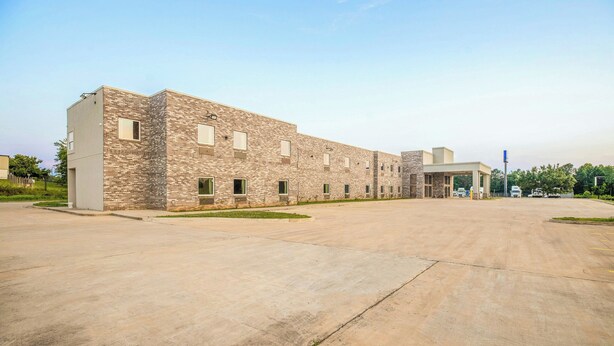 A large building with a flat roof and a paved parking area in front. - OYO Hotel Adairsville Calhoun South I-75 (Adairsville)
