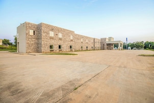 Um edifício grande com telhado plano e área de estacionamento pavimentada na frente.